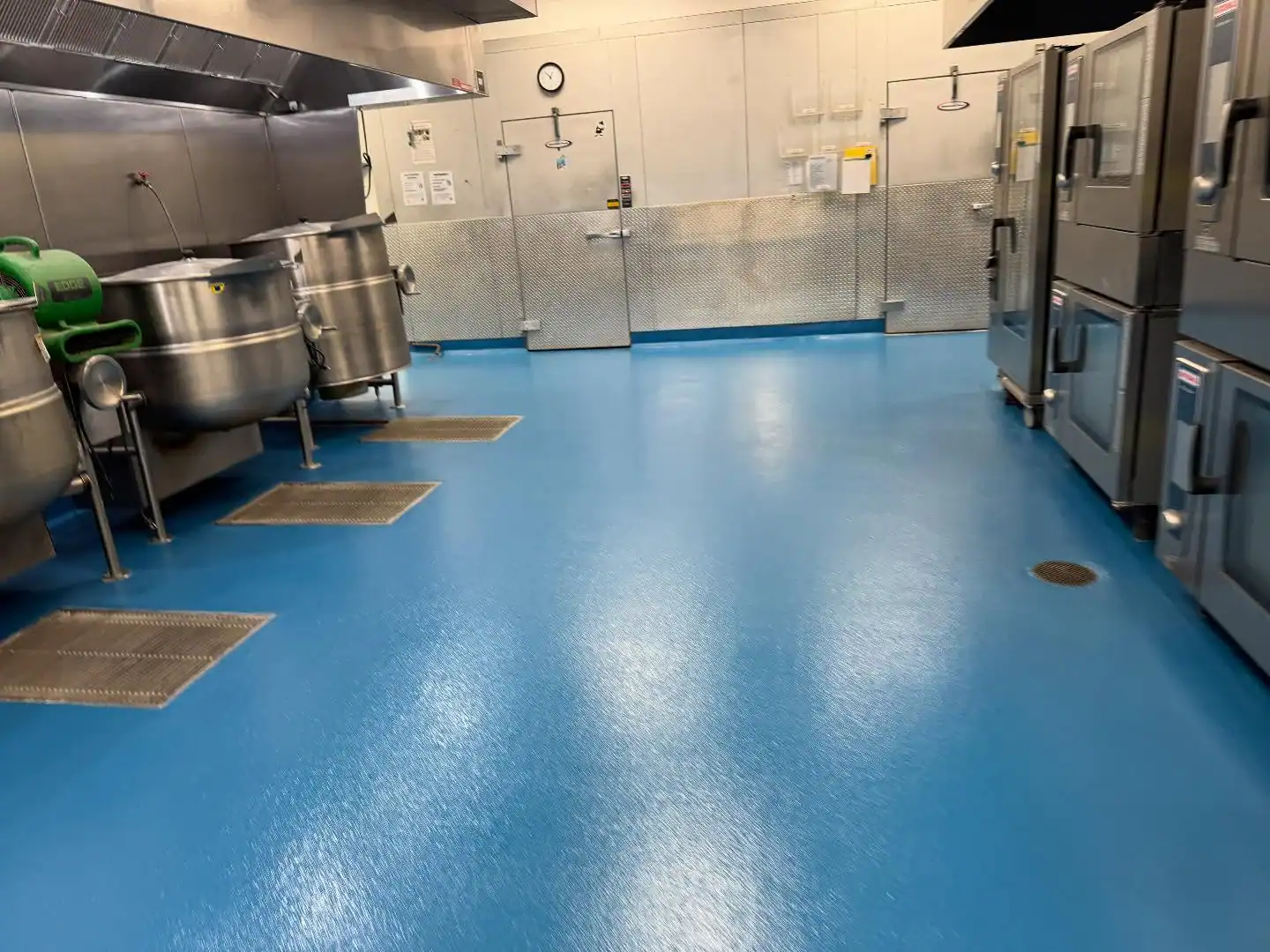 Commercial kitchen in NY featuring blue epoxy floors, stoves, and walk-in fridge by Bohemia contractor.