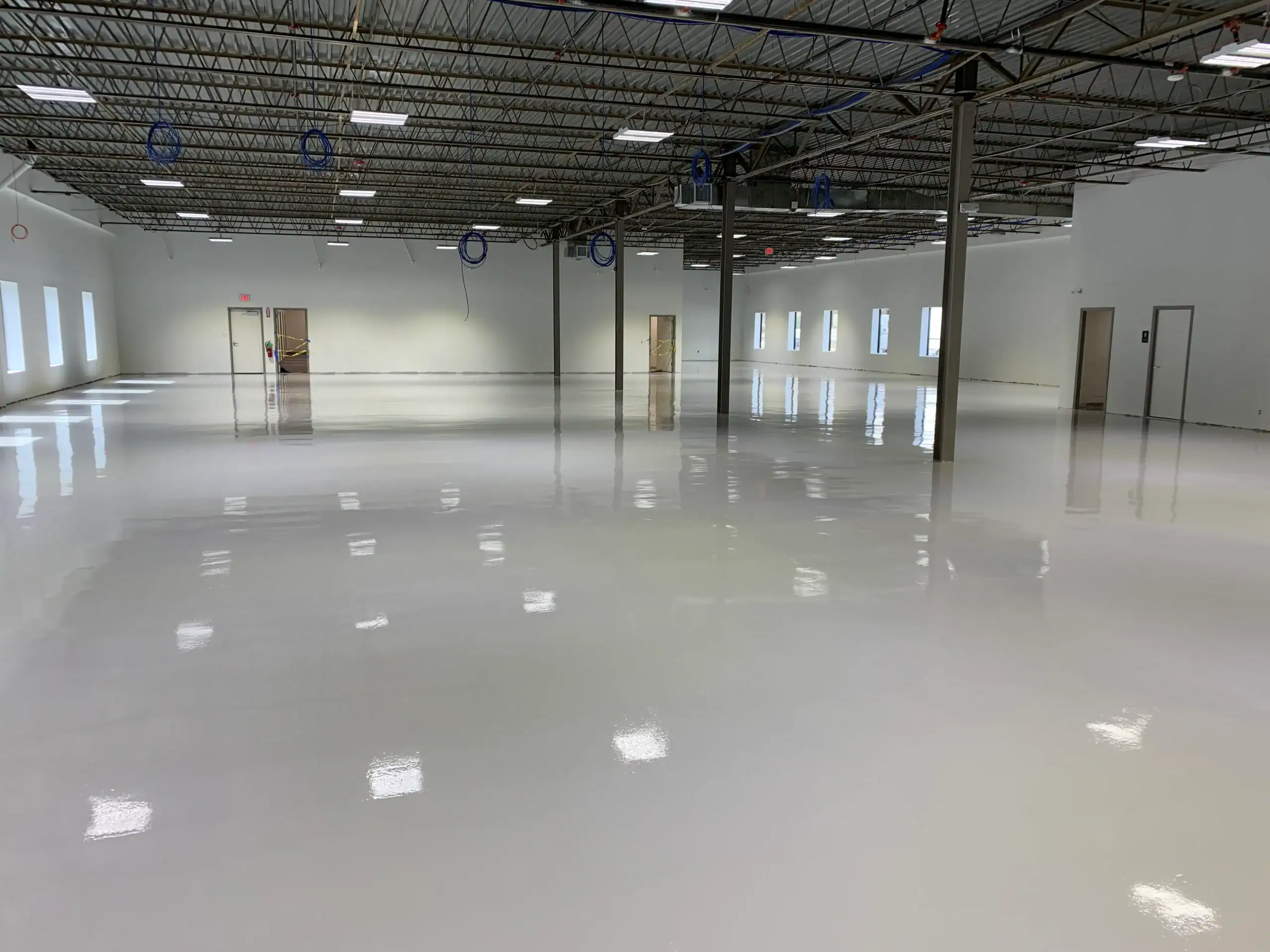 Large warehouse with white epoxy flooring and high ceilings, ideal for an Epoxy Flooring Contractor.